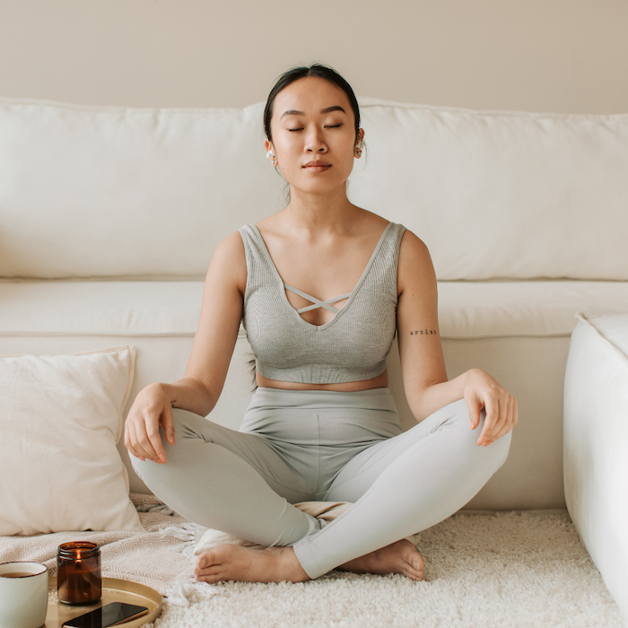 Woman with PCOS sits on living room floor meditating